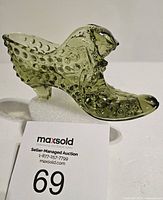 Side view of green glass shoe with hobnail pattern and cat head detail