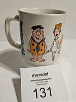 Front side of mug showing Fred Flintstone, Wilma Flintstone, Pebbles Flintstone characters