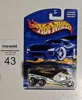 Front view of the Hot Wheels Treasure Hunt Cabin Fever car in sealed packaging showing blue card with flame graphic and limited edition label
