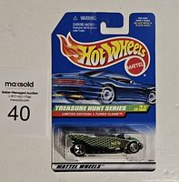 Front view of Hotwheels Treasure Hunt Turbo Flame car in original packaging showing blue card backing, Hotwheels and Mattel logos, and die-cast car with green scaled pattern.