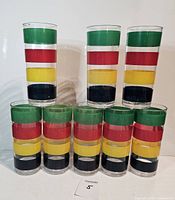 Eight clear acrylic tumblers stacked in a pyramid arrangement showing colored stripes of green, red, yellow, and black.