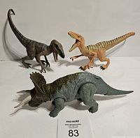 Photo showing three Jurassic World dinosaur toys: two Velociraptors and one Triceratops figure