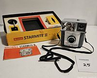 Front view of Kodak Brownie Starmite II camera with original box and manual, showing camera design and accessories included.