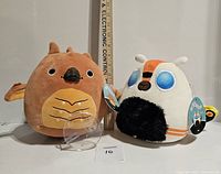 Front view of Rodan (brown) and Mothra (white) Squishmallows plush with ruler measuring about 8 inches tall, new with tags.
