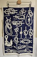 Full view of the rectangular linen cloth with white nautical knot illustrations on a navy blue background and white border.