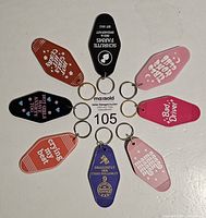 Photo of eight key holders arranged in a circle showing the front printed with quirky sayings.