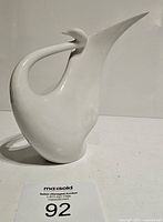 Front left angled view of white ceramic swan figurine with curved neck and pointed beak, marked Royal Dux below