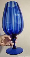 Side angle of sapphire blue Italian art glass vase showing fluted ribbed pattern, glossy finish, and scalloped rim.