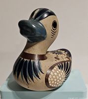Front angle photo of the vintage Tonala pottery duck figurine showing detailed hand-painted feather and floral designs, with natural pottery base color and blue beak.
