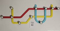 Photo of the full Umbra wall hanger showing red, yellow, and blue rails with multiple round white hooks connected mimicking a subway map route.