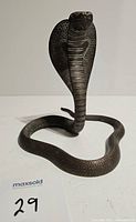 Front view of vintage brass cobra figurine showing raised hood and coiled body with detailed scales.