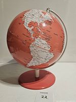 Front view of vintage pink globe showing Americas with detailed labels in black text on coral-pink and white landmasses.