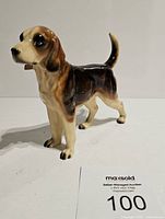 Front angled view of vintage ceramic Beagle figurine showing brown, black, and white detailed markings and glossy finish.
