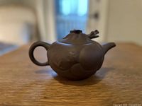 Front angle view of the brown Yixing clay teapot showing the round body and side handle.