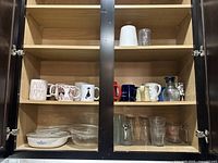 Contents of kitchen cabinet showing mugs, glassware, and bowls on shelves