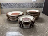 Stacked sets of plates showcasing three different sizes of Mid Century Denby stoneware plates on a countertop.