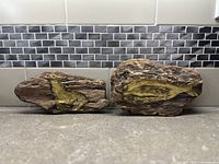 Two driftwood plaques with brushed metal animal figures: seal on left and whale on right.