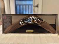 Wooden Jabiru boomerang displayed in a box showing overall shape and artwork
