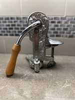 Front view showing wooden handle, grapevine embossed metal body, and lever base.