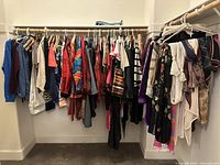 Photo showing an organized closet containing a wide variety of vintage women's clothing items hung on hangers including dresses, blouses, skirts, and scarves.