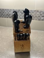 Front view of the vintage wooden knife block with black handled knives and kitchen shears inserted.