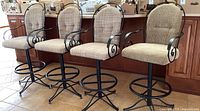 Four metal frame cushioned bar stools arranged in a row, viewed frontally.