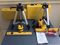 Overview of two laser level kits showing tripods, laser heads, spirit levels, glasses, cases and manual