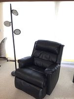 Black recliner chair next to black floor lamp showing overall size and style