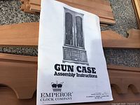 Instruction sheet of gun case cabinet with detailed illustration and brand name Emperor Clock Company.
