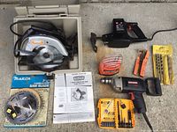 Overview of all items showing the Craftsman circular saw in case, the Makita saw blade in packaging, Sears electric drill, reciprocating saw, drill bit sets, wrench, and orange-handled hand tools.