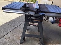 Front perspective of the full table saw on stand showing fence, table top and casters