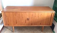 Front angled view of closed cabinet showing teak grain and tapered legs