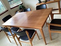 Full view of teak table with six black chairs
