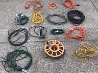 Overview of all extension cords and power reel laid on ground, showing variety of colors and lengths.