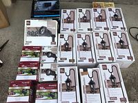 Group photo of multiple garden lantern-style pathway lights, box of 6 low voltage pathway lights (opened with 2 inside), and multiple small spotlight lights in boxes