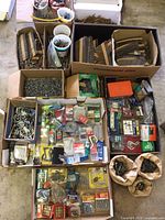 Wide overview photo showing multiple boxes and trays of assorted nails, screws, hooks, fasteners, washers, and hardware items.