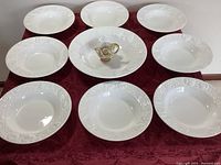 Overview of nine white ceramic pasta bowls and a hand-painted Italian candlestick holder