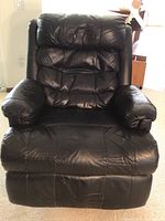 Front view of large black BarcaLounger recliner showing padded cushions and armrests, with some wear on headrest.