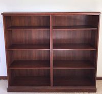 Full front view of the large wooden bookcase showing two main vertical sections and multiple shelves inside.