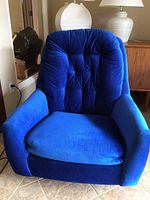 Front view of plush royal blue swivel chair showing tufted backrest and cushioned armrests.