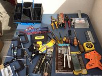 Full overview of all tools arranged on table including tool box, clamps, screwdrivers, tape measures, and rivet tool kits