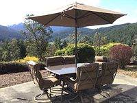 Full view of table, six chairs, umbrella set up outdoors