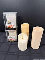 Five flameless wax pillar candles, two boxed Abbott Real Lite and three loose