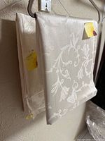 Two folded damask tablecloths hanging on hanger