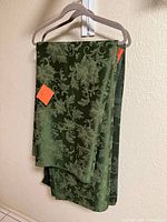 Both folded green floral tablecloths on hangers