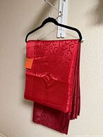 Both red tablecloths folded on hanger