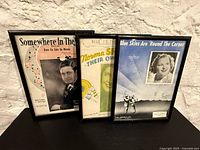 Group shot of three framed vintage sheet-music covers