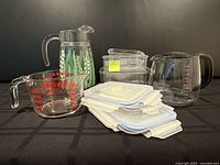Group view of all items: storage containers with lids, Pyrex measuring cup, coffee jug, hand-painted jug