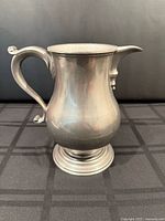 Front view of pewter jug showing overall shape and pedestal foot