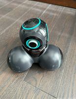 Front angled view of the black Wonder Workshop CUE robot with turquoise detailing on a hardwood floor.